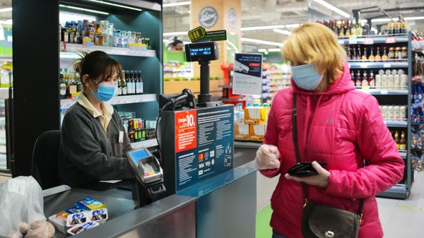 Покупатель оплачивает покупки на кассе в супермаркете Перекресток