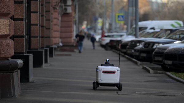 Беспилотный робот-доставщик Яндекса перевозит посылки Почты России на одной из улиц в Москве