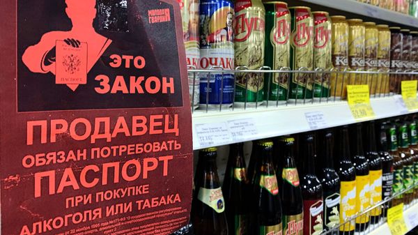 Листовка с надписью Продавец обязан потребовать паспорт при покупке алкоголя или табака на полке с алкогольными напитками в магазине