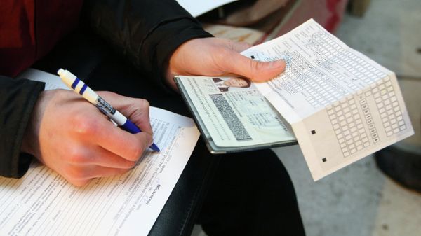 Сотрудник федеральной миграционной службы  проводит проверку документов у иностранных рабочих 