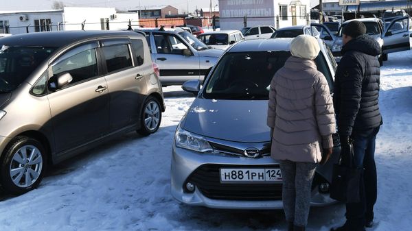 Покупатели у подержанного автомобиля, выставленного на продажу на авторынке