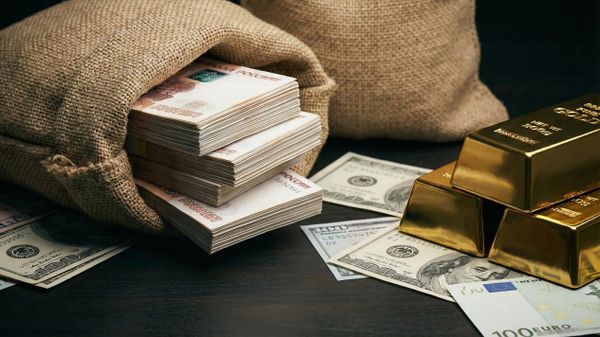 Большие мешки, наполненные российскими рублями, сложены рядом с золотыми слитками и иностранной валютой
