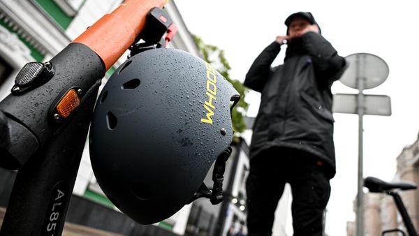 Молодой человек у пункта проката электросамокатов на одной из улиц Москвы