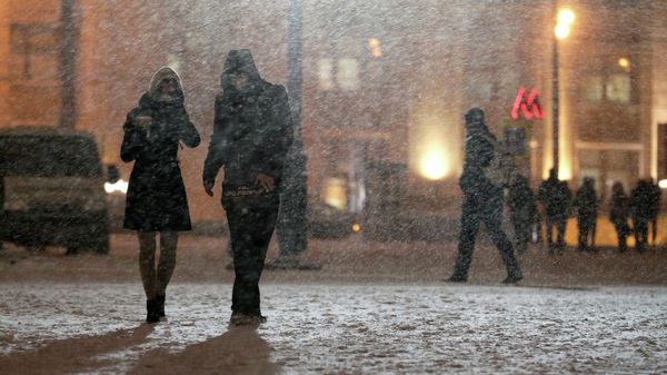 Жители Москвы на одной из улиц города во время снегопада