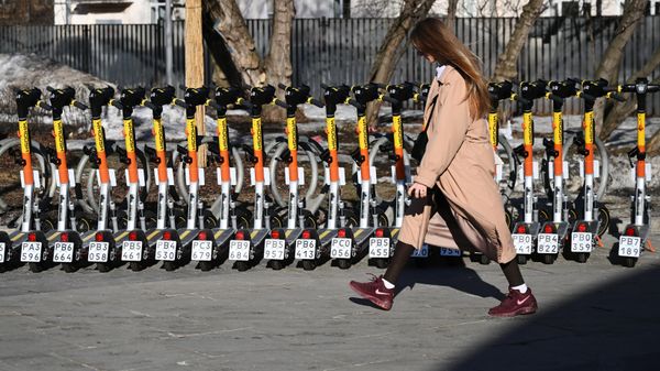 Девушка у пункта электросамокатов на одной из улиц в Москве
