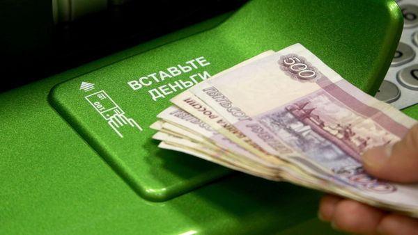 Посетитель банка вносит деньги в банкомат