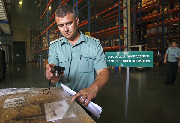 Сотрудник Федеральной таможенной службы досматривает груз