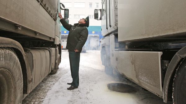 Сотрудник таможни проверяет груз в зоне таможенного контроля Сотрудник таможни проверяет груз в зоне таможенного контроля