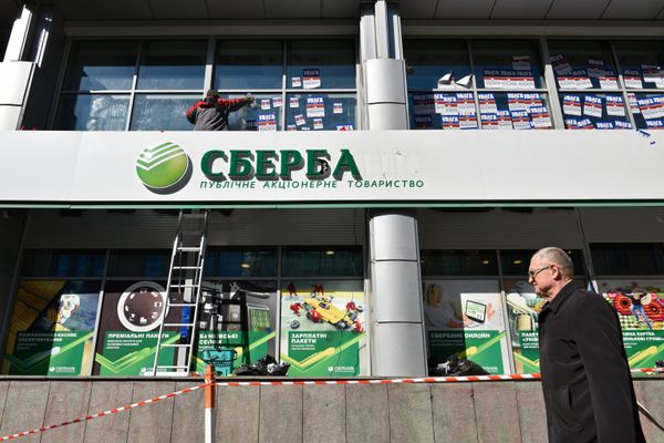 Рабочий очищает фасад центрального отделения дочернего предприятия Сбербанка России в Киеве от листовок. 28 марта 2017