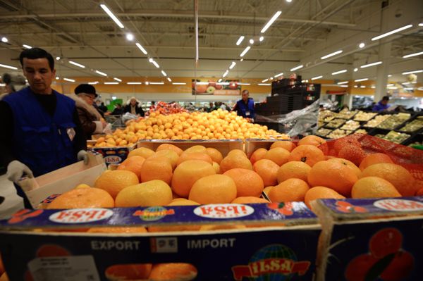 # Продавец у прилавка с мандаринами из Турции в торговом зале гипермаркета Глобус