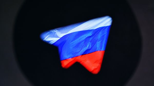 Логотип социальной сети Телеграм на фоне российского флага.