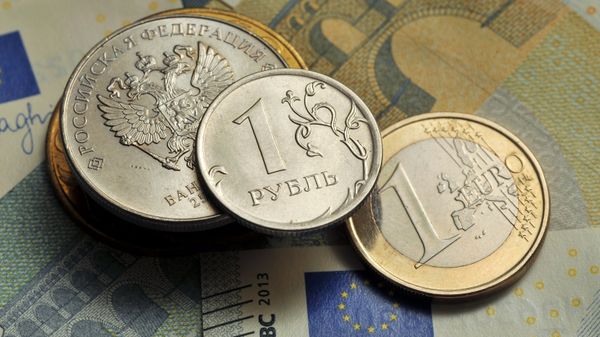 Монеты номиналом 1 рубль и 1 евро на фоне банкноты номиналом 5 евро
