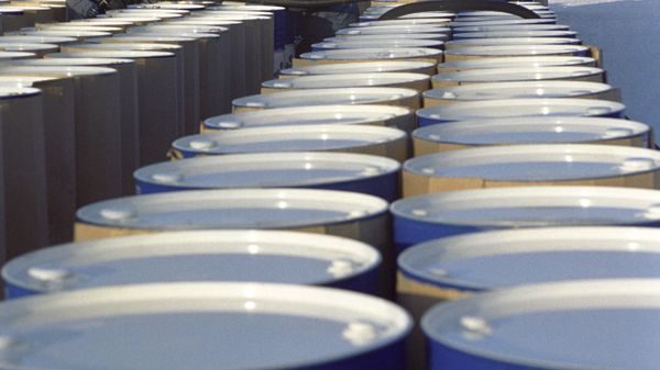 Рабочие заливают топливное масло в нефтяные бочки