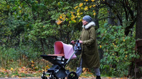 Женщина с детской коляской гуляет в музее-заповеднике Коломенское в Москве